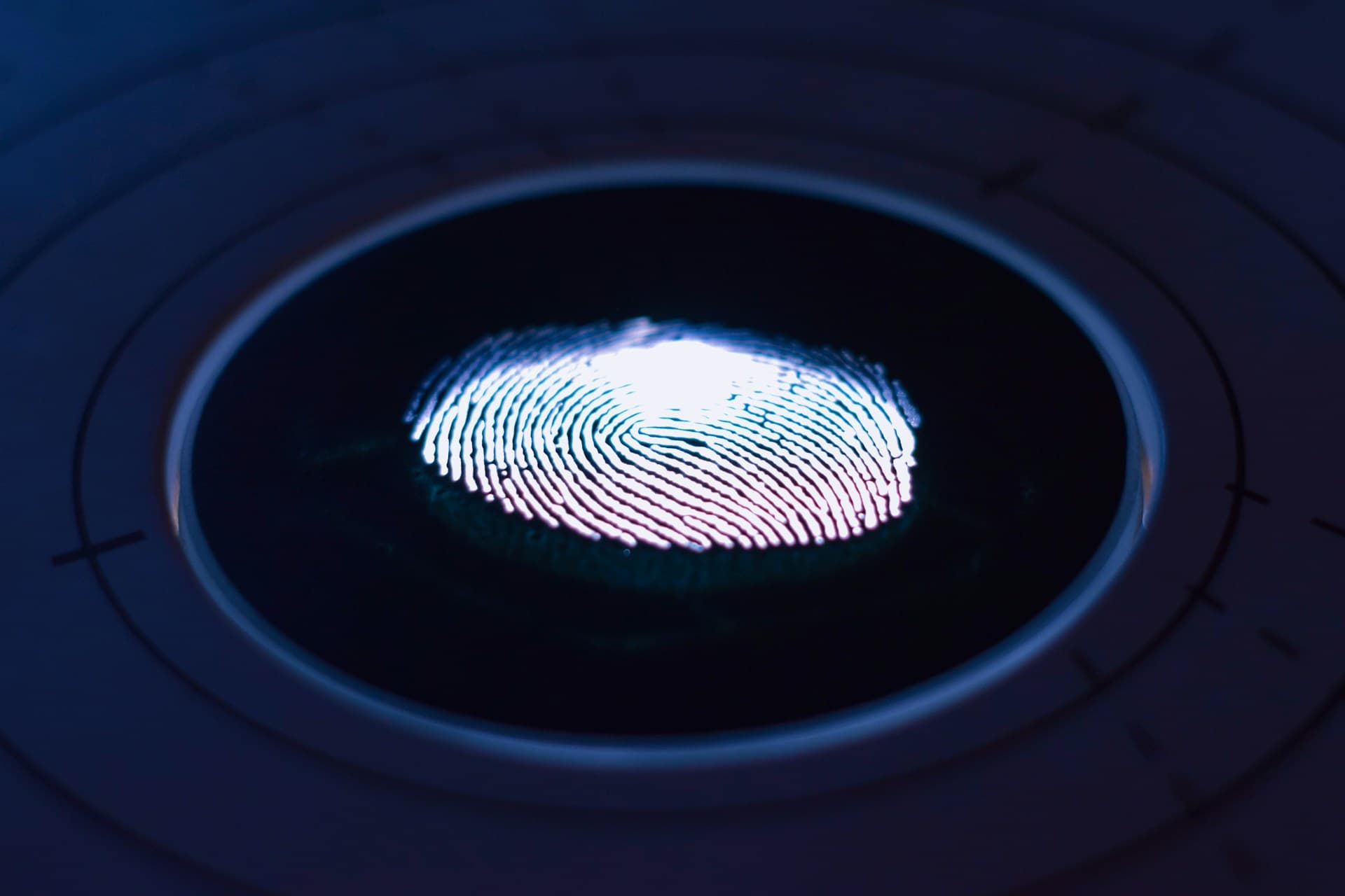 Close-up of an illuminated fingerprint on a touchscreen surrounded by circular lines, highlighting biometric technology.